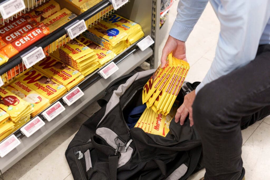 Butikstyv fylder sportstaske med chokolade i en købmandsbutik