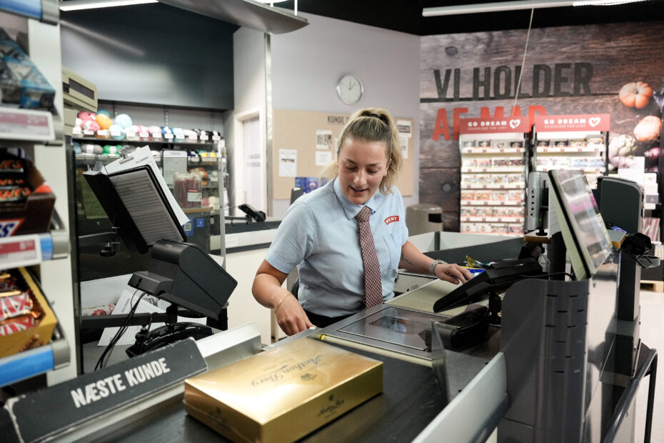 Medarbejder ved kassen scanner en æske chokolade ind