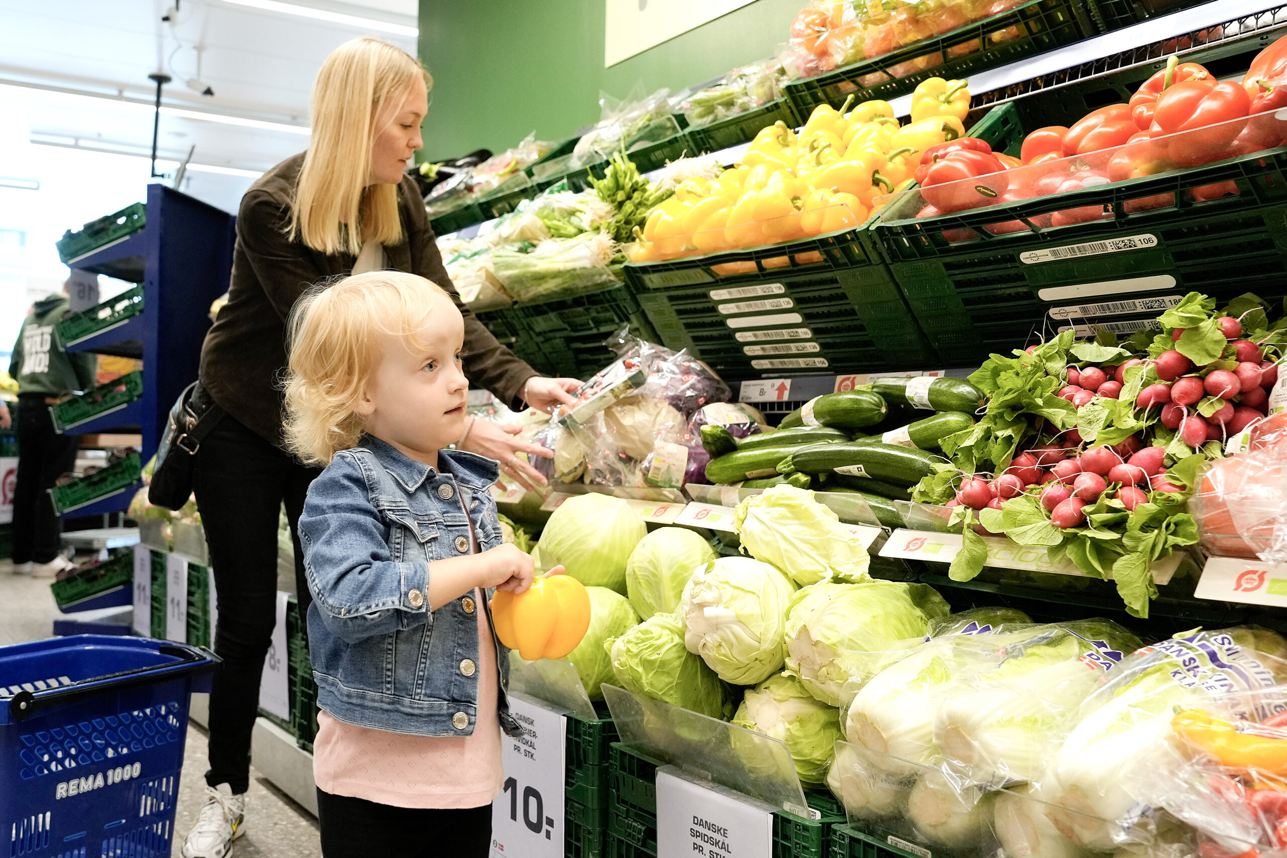Mor og barn handler frugt og grønt hos en købmand