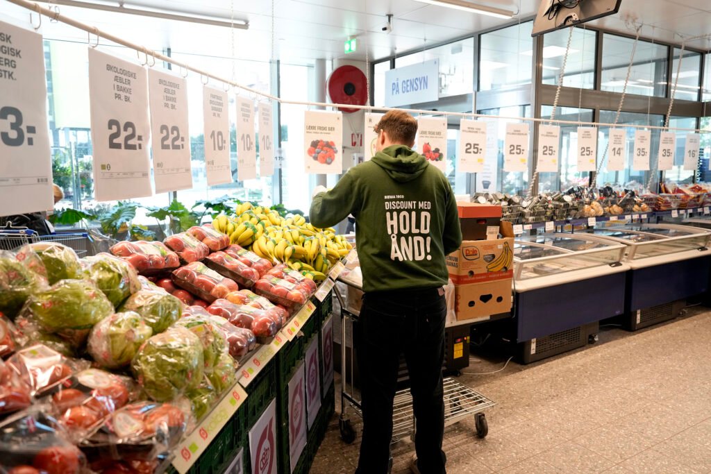 Medarbejder fylder op med frugt og grønt i en købmandsbutik